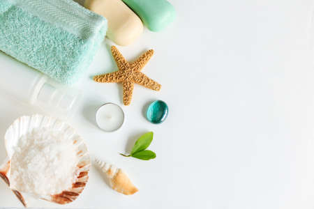 Spa cosmetics and towel with sea stars and salt in the scallop shell on a white background on topの写真素材