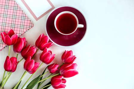 A bouquet of delicate pink tulips with gifts on a white background with a Cup of tea, Holiday conceptの写真素材