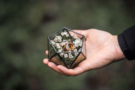Wedding rings made of yellow and white gold are in a glass box. Wedding accessories.