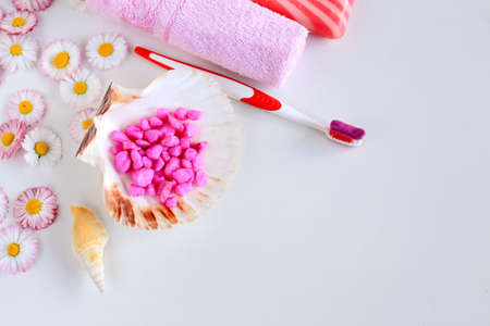 bath accessories lie on a white background with spring flowers. toothbrush with paste, soap and...