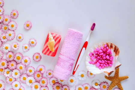 bath accessories lie on a white background with spring flowers. toothbrush with paste, soap and towel on a flat surfaceの写真素材