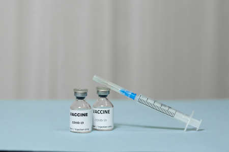 ampoule with a vaccine against coronavirus and syringe on blue surface, vaccination of covid-19,...