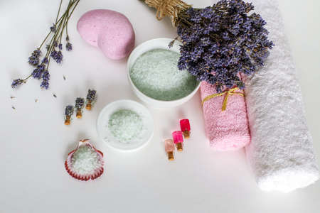 Spa cosmetics and towels, dry lavender, aroma oils and sea salt on a white background