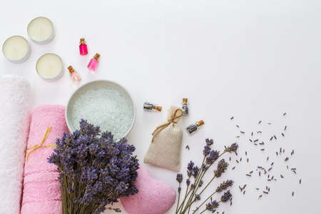 Spa cosmetics and towels, dry lavender, aroma oils and sea salt on a white background with a copy of...
