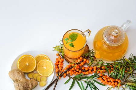 Hot sea buckthorn tea with lemon, ginger and honey on a white table top view. Twigs and berries of sea buckthornの写真素材