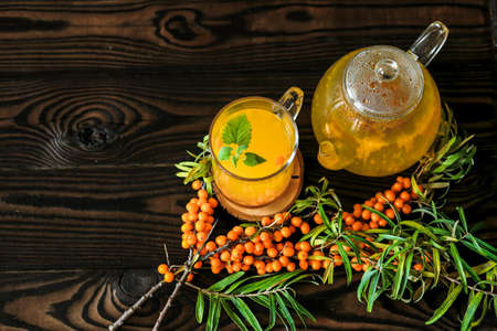 Sea buckthorn tea with lemon, ginger and honey on a dark wooden surfaceの写真素材
