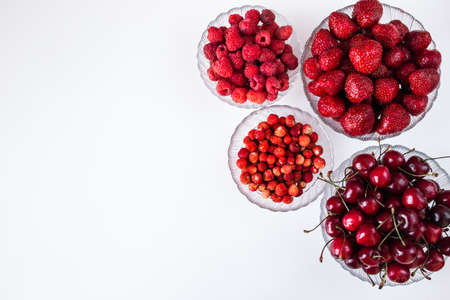 different summer berries in plates on a white surface with a copy of the spaceの写真素材