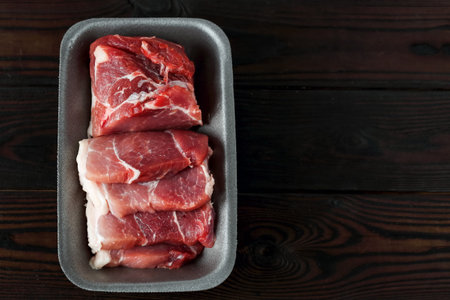 a tray with sliced raw meat steaks on a wooden backgroundの写真素材