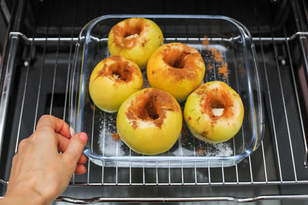 Green apples in a glass container sprinkled with ground cinnamon and stuffed with honey on the grill in the oven. Step 5.step-by-step instructions. Recipe for baked apples in the ovenの写真素材