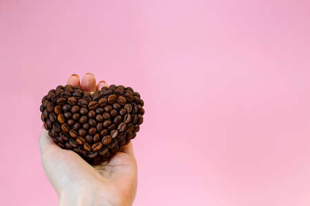 coffee bean heart in hand on pink backgroundの写真素材