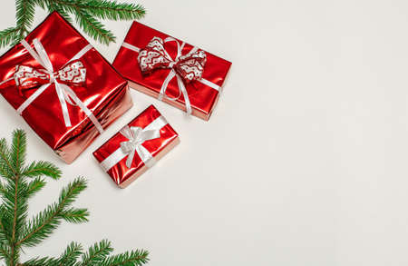 New year's composition, fir branches with gifts in a red wrapper on a vertical white surface, space for textの写真素材