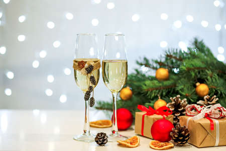 Two glasses of champagne composition with Christmas and new year decorations on a blurry background of burning garlandsの写真素材