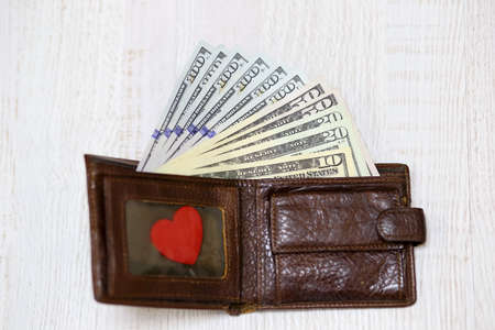 a wallet with various dollar bills, cash in a leather wallet. The concept of the love of money