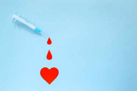 syringe, blood drops and heart on a blue background, world blood donor day, charity and blood...