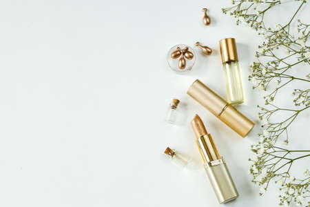 top view of cosmetics in gold tones. lipsticks and perfumed oil on a white background, copy spaceの写真素材