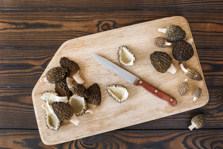 fresh spring mushrooms, morels cut with a knife on a cutting board