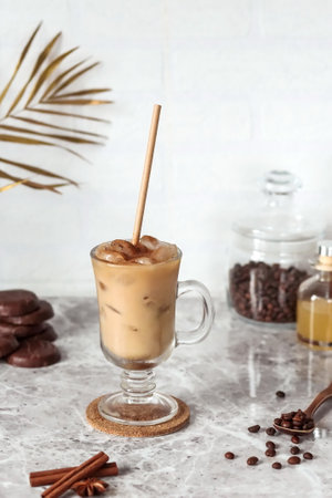 Cappuccino with ice in a tall glass with straws on the table. vertical arrangement