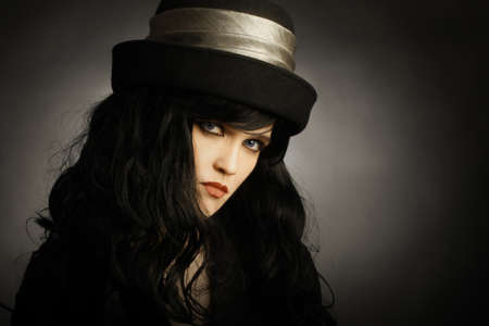 Fashion portrait of young brunette woman in black hat
