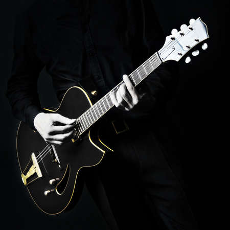 Guitar electric Guitarist playing black music instrument in hands closeup on black