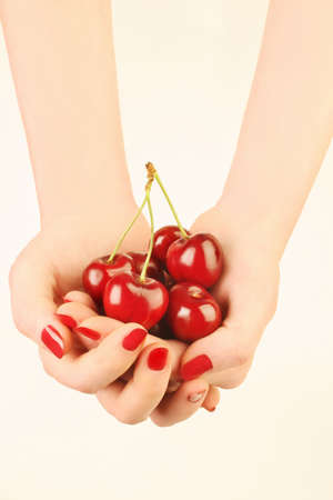 Hands with cherry. Cherries in the woman's hand with red nails manicureの写真素材