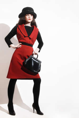 Stylish woman black red dress fashion model in hat with handbagの写真素材