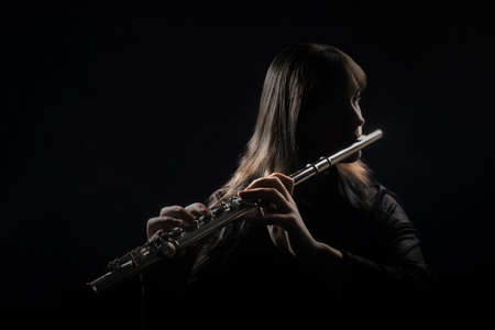 Flute player Flutist playing instrument flute music Classical musician isolated on blackの写真素材