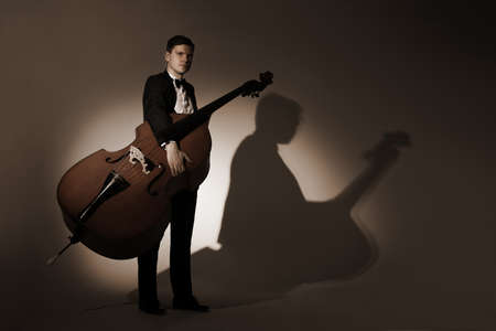 Classical musician studio portrait. Double bass player with contrabass
