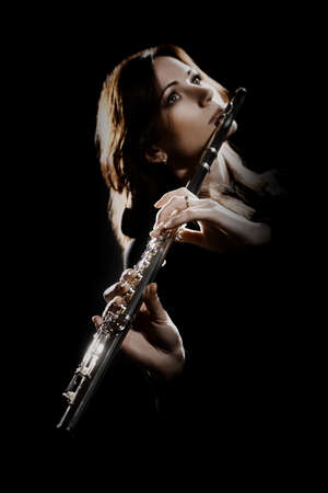 Flute player. Flutist playing flute music instrument. Classical musician woman isolated on black. Focus is on the handsの写真素材