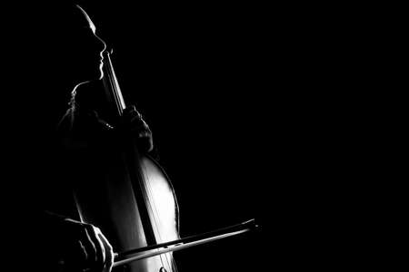cell player. Cellist classical musician playing music instrument in darknessの写真素材