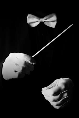 Orchestra conductor music conducting. Hands with baton in white gloves and bowtie isolated on black backgroundの写真素材