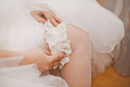The young woman dresses an ornament on a foot before wedding.