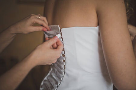 The girlfriend of the bride helps to dress a wedding dress.の写真素材