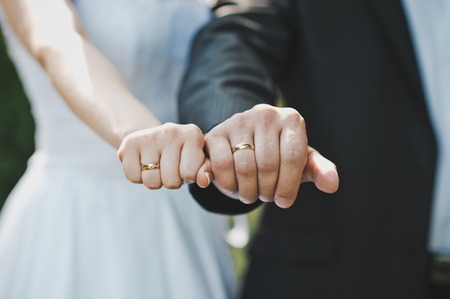 Fists of the newly-married couple with wedding rings in them.の写真素材