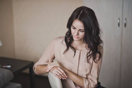 The girl in a shirt and shorts sits on a chair.
