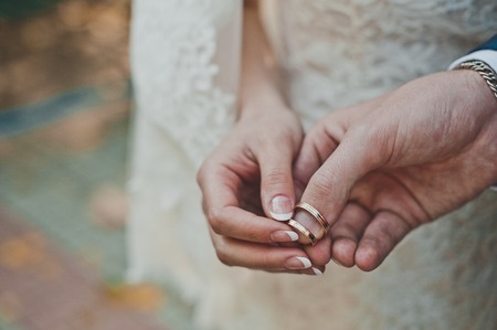 Newly-married couple holds rings on fingers.の写真素材