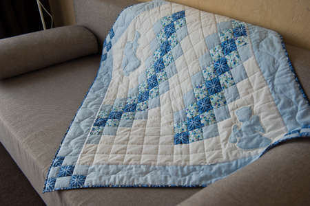 Embroidered by dark blue and white patterns a scrappy blanket.