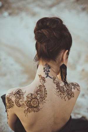 Drawing mehndi by means of henna on hands and a back of the girl.の写真素材