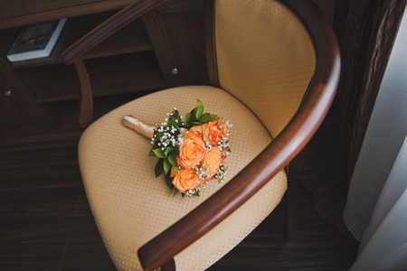 A bouquet of flowers lies on a beige chair.の写真素材