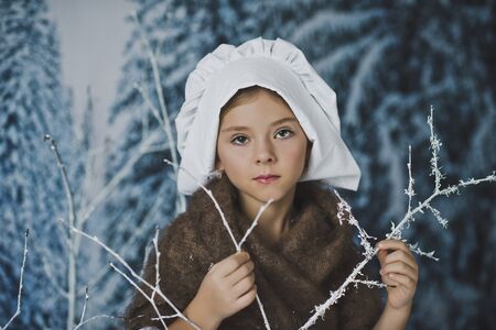 The girl in the white cap among the bushes in the frost.