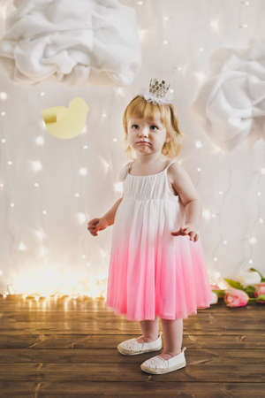 The child wears a crown and a pink dress.の写真素材