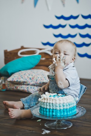 Babe sits and eats cake with his hands.の写真素材