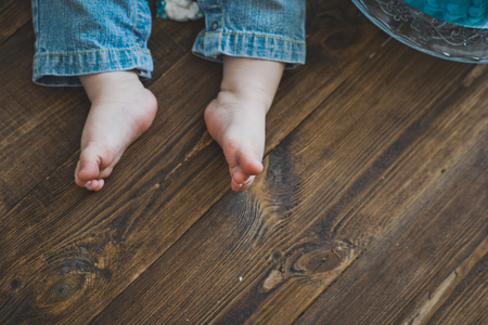 Bare feet baby stand on a wooden floor.の写真素材