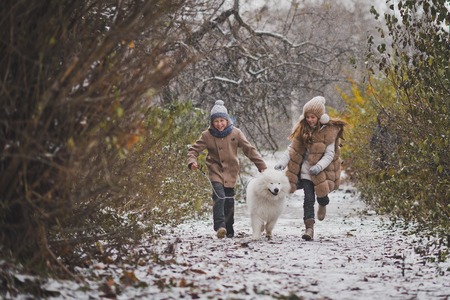 Boy and girl running a race with the Samoyed.の写真素材