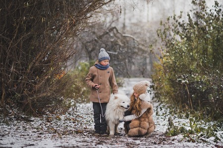 Girl and boy on a walk with the dog breed Samoyed.