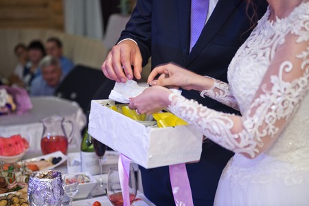 The groom helps the bride to open the gift.の写真素材
