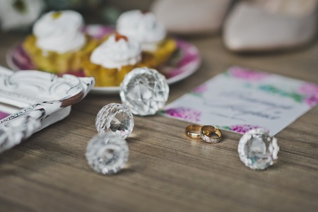 Gold rings newlyweds on the table among the flowers, shoes and cakes.の写真素材