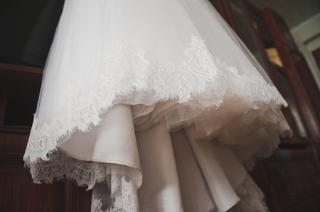 The brides wedding dress hanging on a hanger in the room.の写真素材