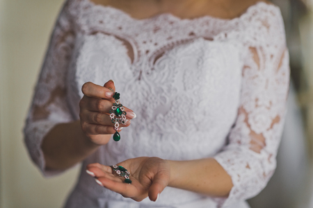 Earrings with green stones in the womens hands.の写真素材