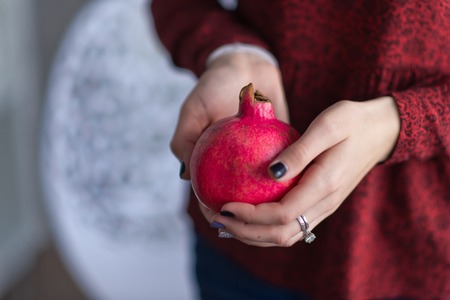 Ripe pomegranate fruit in the girls hands.の写真素材
