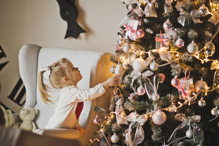 Baby playing with decorations on a Christmas tree.の写真素材